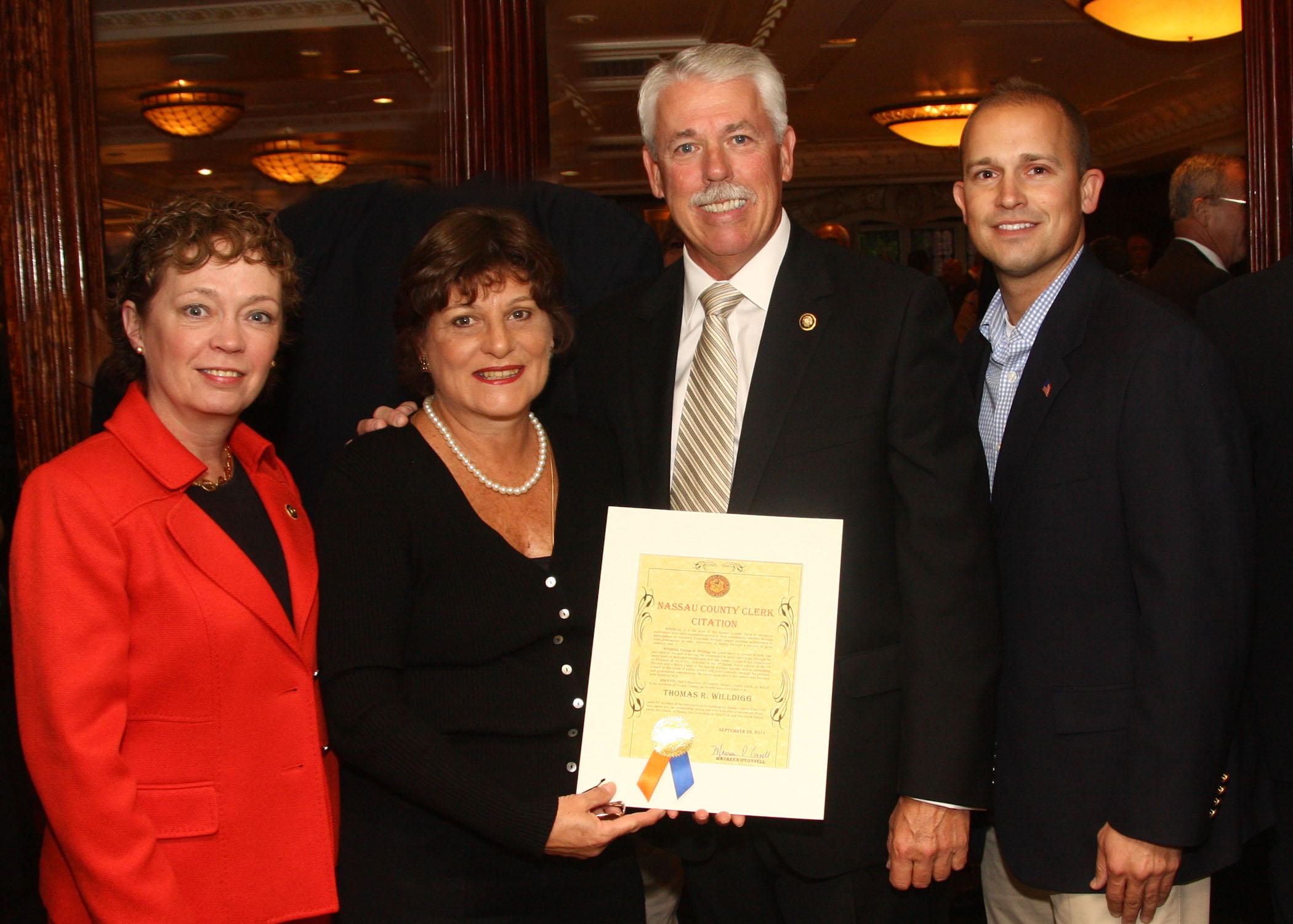 Photo:  Pictured (left to right) are Nassau County Deputy Comptroller Joy Watson, Nassau County Clerk Maureen O'Connell, Detective Thomas Willdigg, and Executive Assistant to the Nassau County Commissioner of Consumer Affairs Kenneth Heino.    